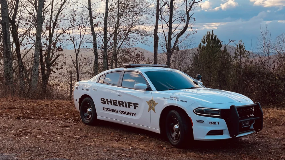 An Etowah County Sheriff’s Office patrol car parked near a wooded hillside